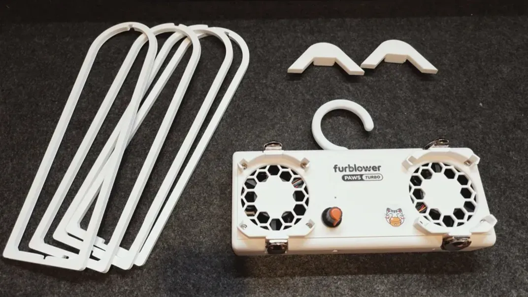 FurBlower PAWS TURBO 主機、桌上支架與架腳平放在深色布面上