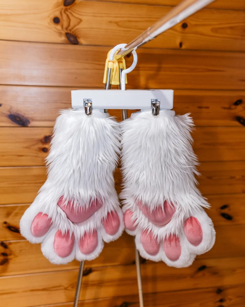FurBlower PAWS 吊掛於衣架上，兩側金屬夾各固定一隻白色毛手