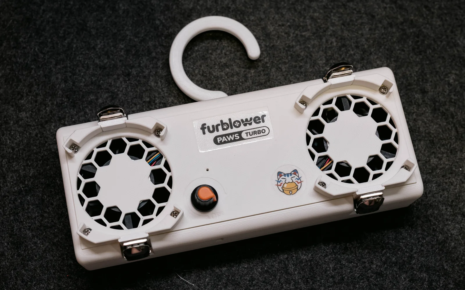 深色布面上斜放的白色 FurBlower PAWS TURBO 雙風扇主機預覽圖